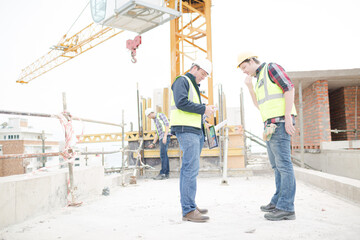 Fototapeta na wymiar Foreman talking to construction worker below crane at construction site