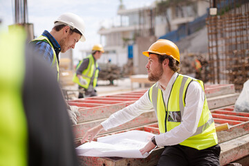 Construction worker engineer reviewing blueprints at highrise construction site