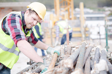 Construction worker carrying metal bar at construction site