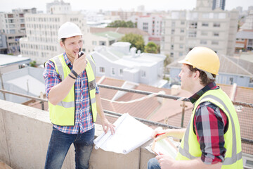 Construction worker engineer reviewing blueprints at highrise construction site