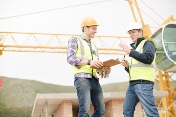 Construction workers with clipboard talking at construction site