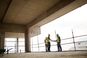 Fototapeta premium Construction workers handshaking at highrise construction site