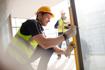 Construction worker measuring window at construction site