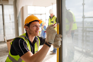 Construction worker measuring window at construction site