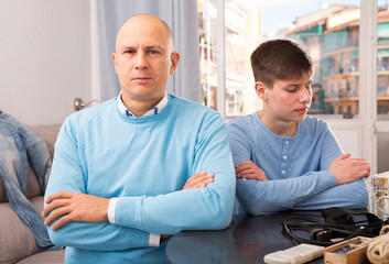 Portrait of offended father after quarrel with son sitting at home