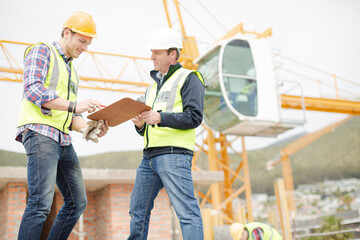 Construction workers with clipboard talking at construction site