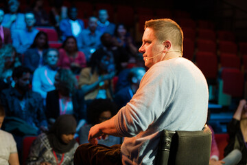Fototapeta na wymiar Audience watching male speaker in wheelchair talking on stage