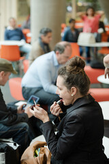 Woman applying make up in hall of auditorium