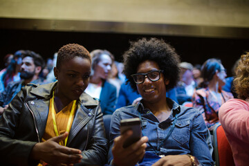 Man and woman with with smart phone in conference audience