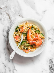 Delicious mediterranean lunch - creamy orzotto with shrimp and zucchini on a marble table, top view