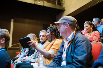 Attentive businesswoman taking in notes in conference audience