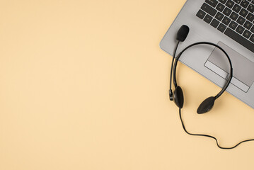 Above photo of laptop and headphones isolated on the beige backdrop with copyspace