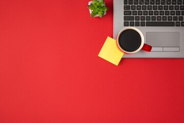 Above photo of laptop plant cup of coffee and yellow sticker isolated on the red backdrop with copyspace