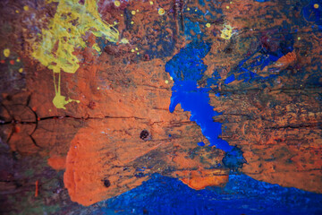 The wooden table is stained with multicolored paints.