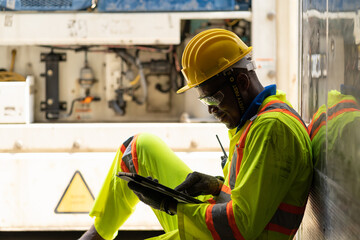 Black worker working at Cargo ship freight. African American male worker working with digital tablet for checking products before loading container from cargo freight shipping for import export