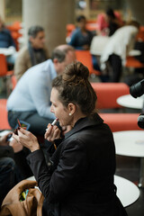 Woman applying make up in hall of auditorium