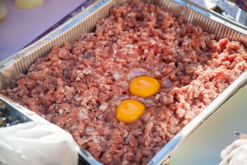 Minced meat and raw egg in a container.