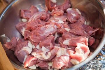 Sliced pieces of fresh meat lie in a metal bowl.