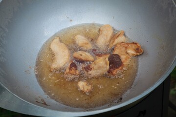 Pieces of lamb fat are fried in a cauldron.