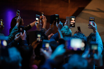 Audience with smart phones videoing conference