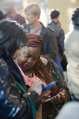 Smiling businesswomen using smart phone in conference audience