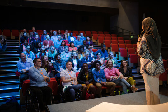 Female speaker in hijab on stage talking to audience