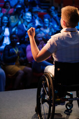 Audience clapping for female speaker in wheelchair on stage