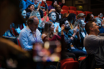 Happy audience clapping in dark room