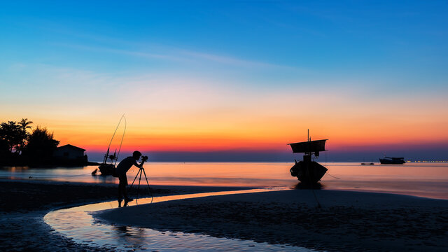 Asia a man nature photographer,Photographer is taking a picture of sunrise at beach with beautiful sky reflections.