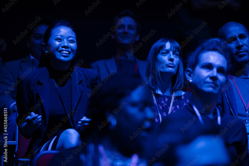 Wall mural Smiling, enthusiastic audience in dark auditorium