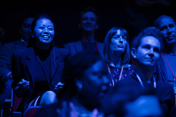 Smiling, enthusiastic audience in dark auditorium