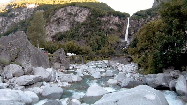 FPV aerial drone shot of waterfall near town of Foroglio, Ticino, Switzerland. Rocky mountainous region, forests and white water river.
