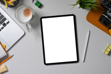 Above view digital tablet with empty display, stylus pen and camera on white desk.