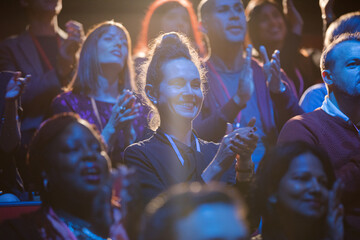 Excited audience clapping in dark room