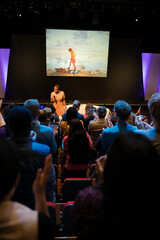 Audience watching male speaker on stage