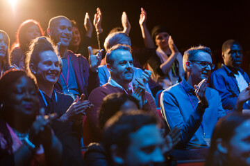 Excited audience clapping in dark room