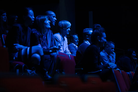 Smiling, enthusiastic audience in dark auditorium