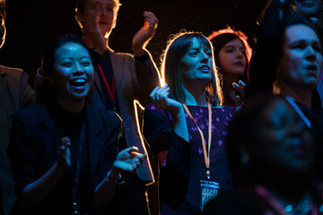 Audience clapping and cheering in dark concert hall