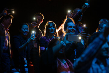 Excited audience with smart phone flashlights cheering