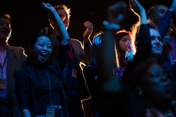 Audience clapping and cheering in dark concert hall