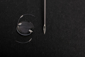 CLOSEUP PHOTO OF INTRAOCULAR LENS (IOL) FOR CATARACT SURGERY COMPARED WITH THE SIZE OF NEEDLE