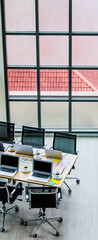 Conference meeting room working table in company office full of laptop notebook computers black hot coffee cups and report data paperwork documents and black chairs with copy space on wooden floor