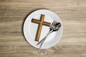 cross on white plate on a wooden table.