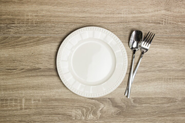 Plate with fork and spoon on a wooden table.