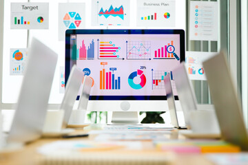 Laptop computer colorful post it paper report data graph chart documents placed on table in...