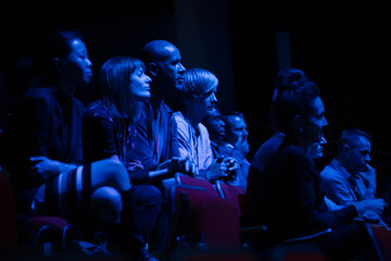 Fototapeta na wymiar Smiling, enthusiastic audience in dark auditorium