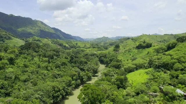 Drone aerial footage of river Rio Cahabon near Semuc Champey National Park in Guatemala surrounded by bright green rainforest trees on a cloudy day. Camera tracking backwards.