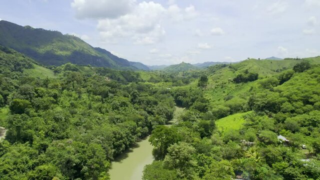 Drone aerial footage of river Rio Cahabon near Semuc Champey National Park in Guatemala surrounded by bright green rainforest trees on a cloudy day near Chicanutz. Camera tracking forwards.
