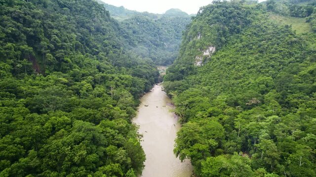 Drone aerial footage of Guatemalan river Rio Cahabon leading up to Semuc Champey National Park, Guatemala surrounded by bright green rainforest hillsides and mountains. Camera tracking forwards.