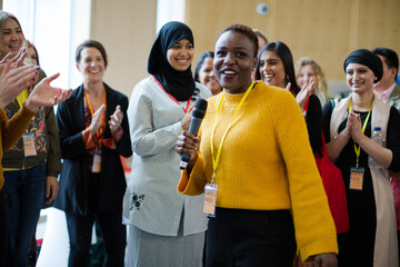 Smiling female speaker with microphone on stage